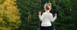 Little girl from the back swinging on a swing