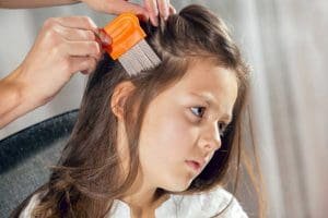 Parent using head lice comb in daughters hair