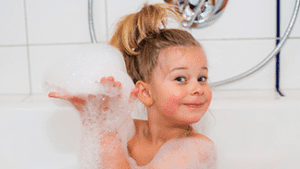 Little girl in the bathtub happy with bubbles