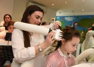 Technician performing heated air head lice treatment on child