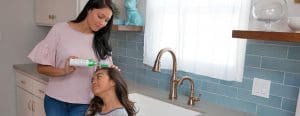 Mom applying lice clinics of america lice remover gel to daughters hair