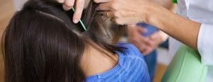 Technician looking at the back of a girls head with a regular comb