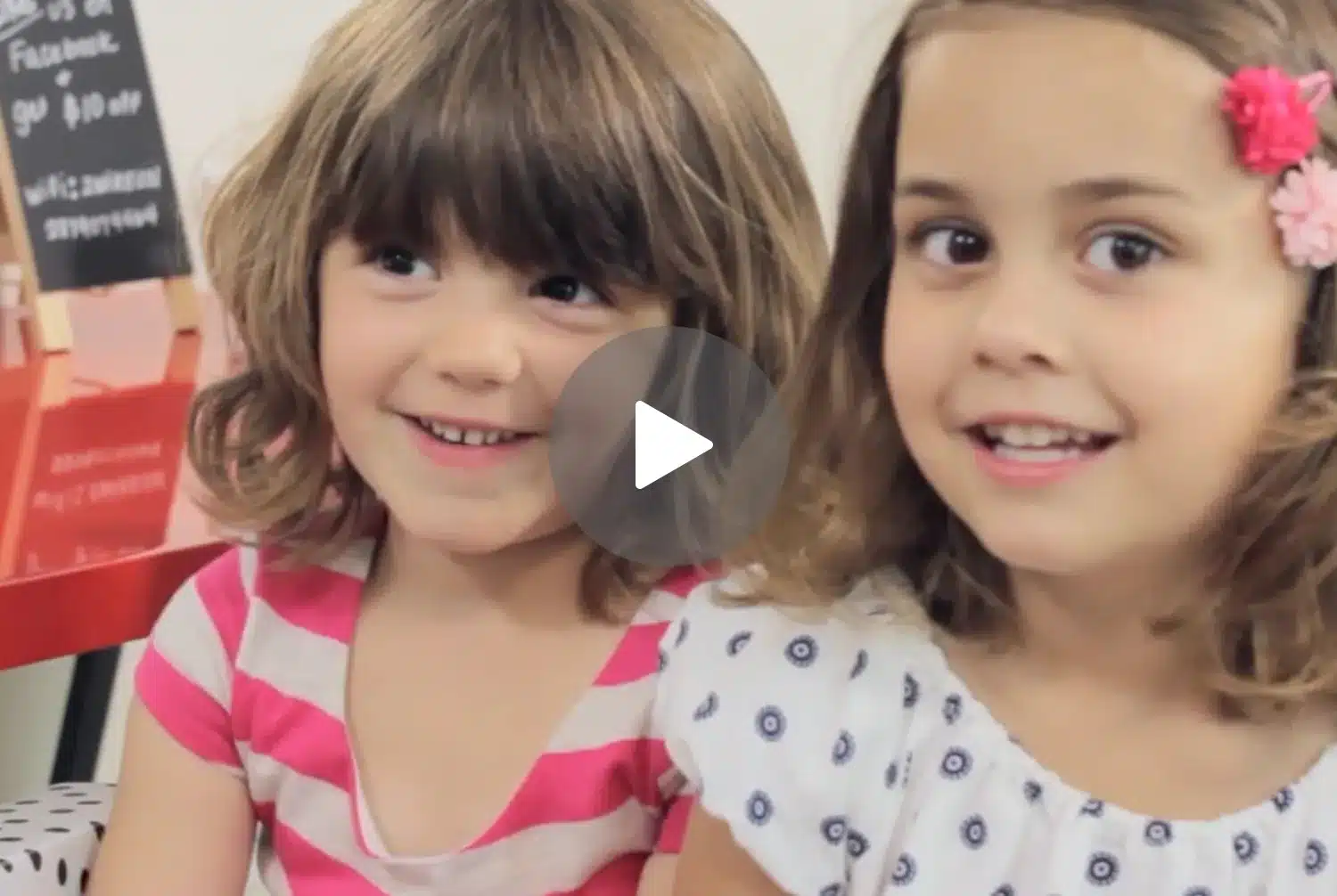 Two young girls smiling at the camera in a lice clinic