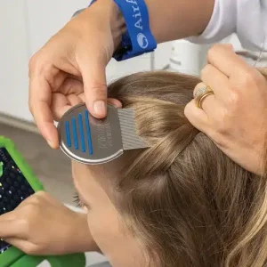 Close-up of a technician using a lice comb to check a child’s hair for head lice.