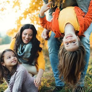 Family outside with dad holding daughter upside down
